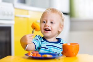 Cute child little boy eating healthy food in kitchen